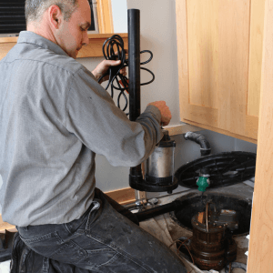 plumber installing sump pump to prevent future water extraction and damage